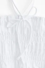 Top blanco de algodón con escote recto, breteles finos y volado en el bajo.