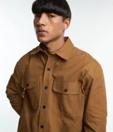Camisa marrón de manga larga, confeccionada en sarga, con cuello inglés, abotonado delantero, bolsillos en el pecho con solapa y puños abotonados.