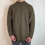 Sweater verde oliva de tejido grueso con cuello alto.