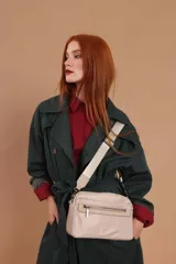 Bandolera color rosa viejo con detalles en cuero marrón claro, múltiples cremalleras metálicas y herrajes plateados. Incluye correa ancha ajustable con el logo de la marca.