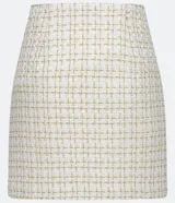 Minifalda negra de tweed con estampado a cuadros en dorado, con tres botones decorativos en el frente y abertura lateral.