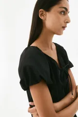 Vestido corto evasé negro en tejido de algodón con vuelo, mangas globo cortas de diseño raglán y escote redondo con cordón para ajustar.