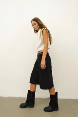 Bota negra de cuero con caña alta y detalle de cobertura de gamuza negra en la parte superior.