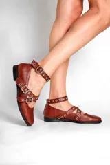 Chatas de cuero color marrón con tiras cruzadas con hebillas y tachas plateadas.