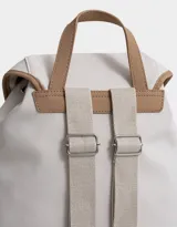 Mochila azul marino con detalles en cuero sintético color camel. Tiene solapa superior con cierre de hebilla, doble bolsillo frontal con hebilla, correa de ajuste y manija superior.