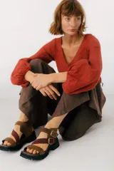 Sandalias de cuero marrón con tiras cruzadas y hebillas doradas.