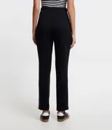 Pantalón zanahoria negro de punto roma, con cintura lisa, bolsillos laterales y pliegues delanteros.