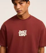 Remera color ladrillo de corte relaxed, confeccionada en tejido de punto de algodón. Tiene cuello redondo, mangas cortas y estampa frontal con la frase "Soul's Chase" en color crema.