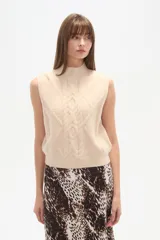 Chaleco sin mangas color beige, con cuello alto y tejido de ochos.