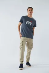 Pantalón cargo color marrón, corte slim, con cierre y botón en la cintura, pasacintos y bolsillos cargo con botones.
