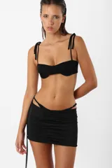 Minifalda negra de microfibra con tiro bajo, corte ajustado y frunces en el delantero. Incluye panty de microtul unida a la falda mediante tiras y argolla.