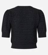 Blusa negra de manga corta con cuello redondo y textura de punto con patrón de corazones o escamas.