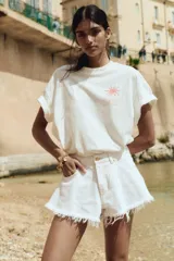 Short de jean blanco de tiro alto, con cinco bolsillos, corte holgado y bajo desflecado.