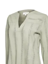 Blusa de manga larga color verde claro, confeccionada en algodón orgánico. Presenta escote en V, puños definidos y calado en la tela.