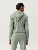 Campera deportiva verde con capucha, cierre frontal y bolsillos laterales. Confeccionada en tejido Air_Tech ultraligero de secado rápido.