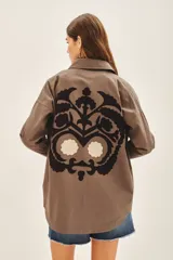 Campera manga larga color marrón con cuello camisero, confeccionada en gabardina con parches bordados en delantero y espalda.