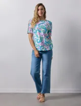 Remera estampada con diseño paisley en tonos celeste, rosa, amarillo y verde. Tiene mangas cortas con detalle de aberturas y lazos en los hombros.