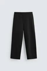 Pantalón jogger negro de corte ancho, confeccionado en tejido de algodón con interior de rizo. Cuenta con cintura elástica ajustable con cordón interior, bolsillos laterales y bolsillo trasero de parche.