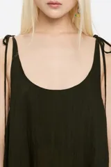 Vestido midi verde oscuro de corte amplio, con breteles finos que se atan en los hombros.