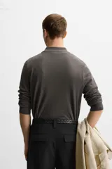 Polo de hombre color gris oscuro, de punto ligero tejido en hilatura con mezcla de seda y algodón. Tiene cuello solapa con cierre frontal de botonadura, manga larga y acabados en rib.