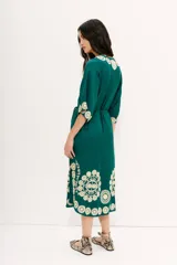 Vestido tipo túnica largo midi de viscosa color verde esmeralda con bordados florales en color crema. Tiene mangas al codo y lazo de ajuste en la cintura.