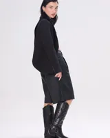 Bota texana de cuero negro con bordados en el caño, punta fina y correa con hebilla metálica.