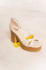 Sandalias de cuero color marrón con plataforma de madera y taco cuadrado. Tiras cruzadas en el empeine y pulsera al tobillo con hebilla dorada.