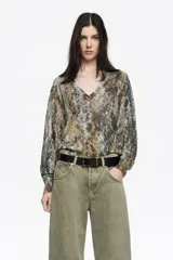 Sweater de punto con escote en V y manga larga, de corte recto. Presenta un diseño con estampado animal print en tonos neutros y fibras metalizadas que aportan un brillo sutil.