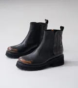 Botas Chelsea de cuero vacuno negro con elásticos laterales, cierre interno y suela de goma artesanal.