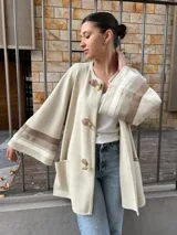 Saco color crema de tejido fino de lana con detalles de cintas tejidas en mangas y bolsillos.