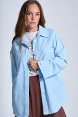 Sobrecamisa negra de gabardina con cuello camisero, cierre frontal con botones, mangas largas con puños abotonados y bolsillos de parche en el pecho.