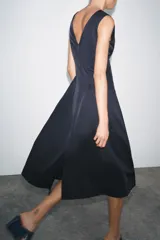 Vestido midi azul marino confeccionado en hilatura con algodón. Escote pico y tirantes anchos. Bajo evasé. Cierre frontal con cremallera metálica.