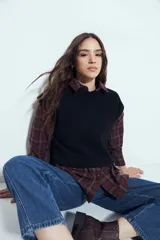 Chaleco tejido sin mangas de color negro, con cuello redondo y diseño de textura sutil. Presenta un corte recto con terminaciones acanaladas en el ruedo y hombros levemente estructurados.