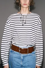 Camiseta de manga larga a rayas horizontales blancas y negras, con cuello redondo y bajo con aberturas laterales.