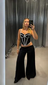 Corset negro con copas preformadas y varillas, con tirantes finos blancos y ribete blanco en el contorno.