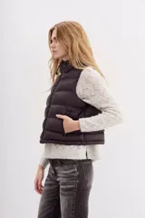 Chaleco puffer negro con cuello alto y cordón de ajuste en el ruedo.