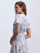 Vestido midi estampado con flores color celeste y beige, escote cruzado, mangas cortas con puños elastizados, cintura elastizada con lazo de ajuste.