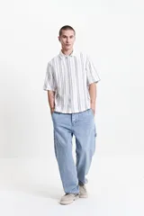 Camisa oversize de manga corta con rayas verticales grises y blancas, estilo rústico.