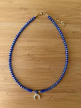 Gargantilla corta de cuentas facetadas color azul eléctrico, separadores dorados y dije de media luna con strass.