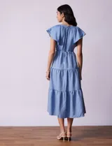 Vestido midi celeste de tencel con cuello a la base y escote en V. Cintura con frunces y lazo de ajuste. Terminación de ruedo con volado.