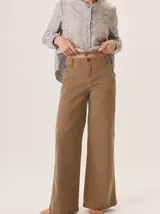 Pantalón de jean color marrón claro, tiro medio/alto, con pierna recta y holgada. Presenta costuras a contratono y cierre frontal con botón.