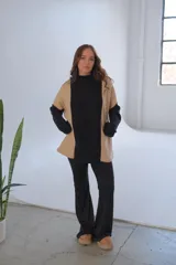 Conjunto de viscosa con felpa, compuesto por un buzo de cuello alto con mangas largas en color negro y paneles laterales en color beige, y un pantalón Oxford negro.