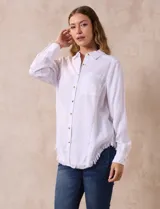 Camisa blanca de lyocell, marca Hester & Orchard. Tiene cuello con solapa, abertura central con botones, bolsillo aplicado en el pecho y ruedo desflecado.