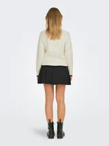 Sweater de punto color crema con diseño de trenzas y punto arroz. Tiene cuello redondo y mangas largas con puños y bajo acanalados con borde negro.