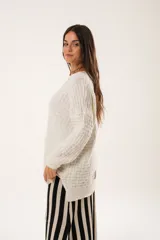 Buzo oversize color beige confeccionado en tejido sintético con destellos de lurex, cuello redondo y manga larga.