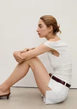 Short de jean blanco, tiro medio, con bajo deshilachado y diseño de cinco bolsillos.