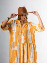 Vestido midi de algodón con estampado abstracto en tonos naranja, blanco y beige. Tiene cuello mao, mangas 3/4 y corte amplio con volados.