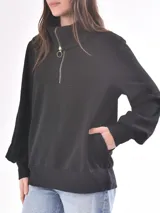 Buzo de punto color rosa con cuello alto con cierre de cremallera metálica y mangas largas abullonadas.
