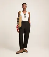 Pantalón zanahoria de poliéster color negro, con cintura elástica en la espalda, pliegues delanteros y abotonado frontal.