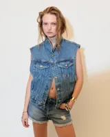 Chaleco de denim celeste con cuello alto, mega sisa y corte boxy. Tiene bolsillos plaqué en el pecho, bolsillos ojal en los laterales y presillas en el ruedo trasero para ajustar.